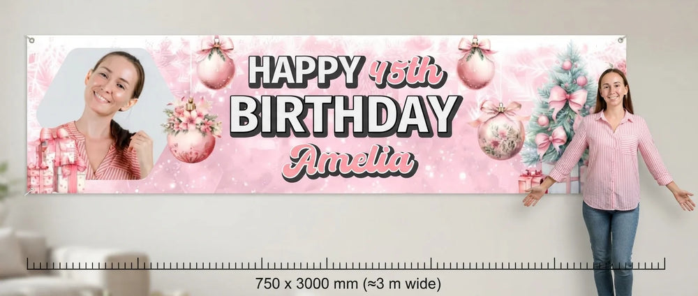 Person standing beside the Pink Christmas Birthday Party Banner for scale, with size guide showing 750 x 3000 mm