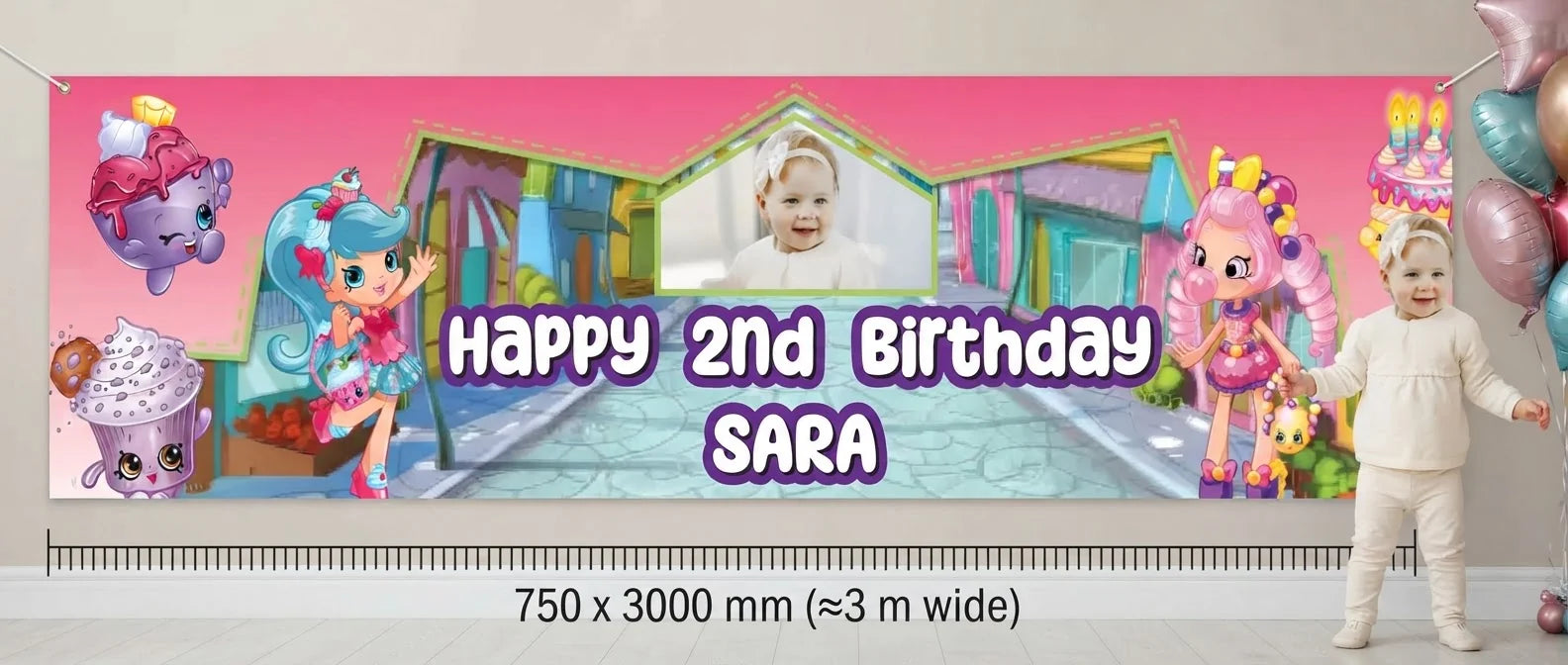 Person standing beside the Shopkins Birthday Banner for scale, with size guide showing 750 x 3000 mm